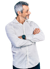 Middle age hispanic with grey hair wearing casual white shirt looking to the side with arms crossed...