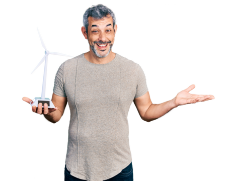 Middle age hispanic with grey hair holding solar windmill for renewable electricity celebrating achievement with happy smile and winner expression with raised hand