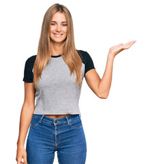 Fototapeta premium Young blonde woman wearing casual clothes smiling cheerful presenting and pointing with palm of hand looking at the camera.