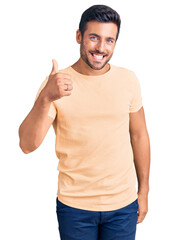 Young hispanic man wearing casual clothes doing happy thumbs up gesture with hand. approving expression looking at the camera showing success.