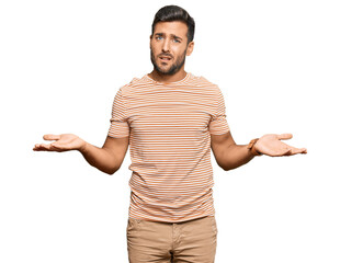 Handsome hispanic man wearing casual clothes clueless and confused with open arms, no idea concept.