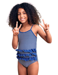 African american child with curly hair wearing swimwear smiling looking to the camera showing...