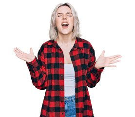 Young blonde girl wearing casual clothes crazy and mad shouting and yelling with aggressive expression and arms raised. frustration concept.