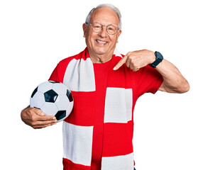 Senior man with grey hair football hooligan holding ball looking confident with smile on face,...