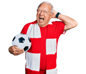 Senior man with grey hair football hooligan holding ball crazy and scared with hands on head, afraid and surprised of shock with open mouth