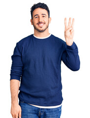 Young hispanic man wearing casual clothes showing and pointing up with fingers number three while smiling confident and happy.