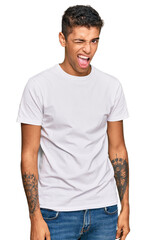 Young handsome african american man wearing casual white tshirt winking looking at the camera with sexy expression, cheerful and happy face.