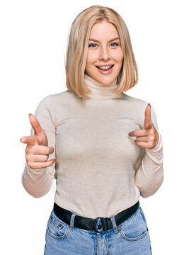 Young blonde woman wearing casual clothes pointing fingers to camera with happy and funny face. good energy and vibes.