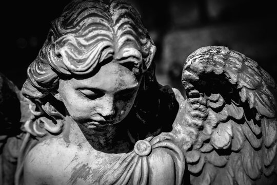 Sculpture of an angel with dark background. Antique statue. Black and white image.