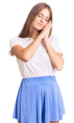 Young beautiful blonde woman wearing summer style sleeping tired dreaming and posing with hands together while smiling with closed eyes.