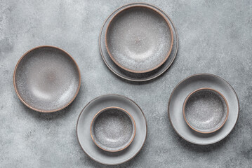 Empty plates on grunge gray background. A collection of various craft plates. Handmade ceramics....