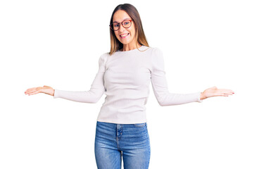 Beautiful brunette young woman wearing casual white sweater and glasses smiling showing both hands open palms, presenting and advertising comparison and balance