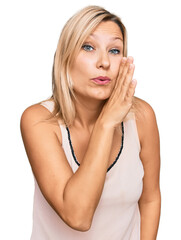 Middle age caucasian woman wearing casual clothes hand on mouth telling secret rumor, whispering malicious talk conversation