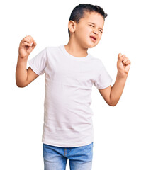 Little cute boy kid wearing casual white tshirt very happy and excited doing winner gesture with...