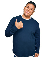 Young latin man wearing casual clothes doing happy thumbs up gesture with hand. approving...