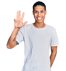 Young hispanic man wearing casual white t shirt showing and pointing up with fingers number four while smiling confident and happy.