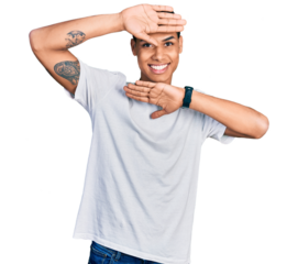 Young hispanic man wearing casual white t shirt smiling cheerful playing peek a boo with hands showing face. surprised and exited