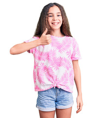 Cute hispanic child girl wearing casual clothes doing happy thumbs up gesture with hand. approving expression looking at the camera showing success.