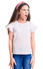 Fototapeta premium Cute hispanic child girl wearing casual white tshirt angry and mad screaming frustrated and furious, shouting with anger. rage and aggressive concept.