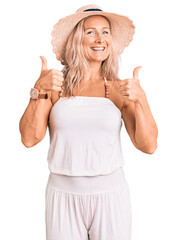 Middle age fit blonde woman wearing summer hat success sign doing positive gesture with hand, thumbs up smiling and happy. cheerful expression and winner gesture.