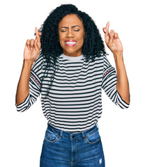 Middle age african american woman wearing casual clothes gesturing finger crossed smiling with hope and eyes closed. luck and superstitious concept.
