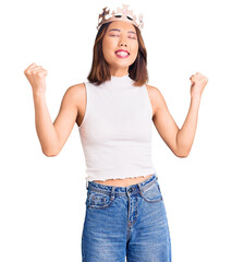 Young beautiful chinese girl wearing princess crown very happy and excited doing winner gesture with arms raised, smiling and screaming for success. celebration concept. © Krakenimages.com