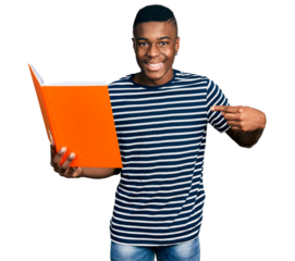 Young african american man holding book pointing finger to one self smiling happy and proud