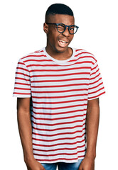 Young african american man wearing casual t shirt and glasses winking looking at the camera with sexy expression, cheerful and happy face.