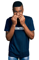 Young african american man wearing volunteer t shirt laughing and embarrassed giggle covering mouth with hands, gossip and scandal concept