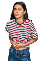 Young hispanic girl wearing casual clothes with hand on stomach because indigestion, painful illness feeling unwell. ache concept.