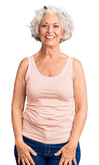 Senior grey-haired woman wearing casual clothes looking positive and happy standing and smiling...