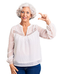 Senior grey-haired woman wearing casual clothes smiling and confident gesturing with hand doing small size sign with fingers looking and the camera. measure concept.