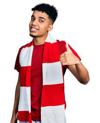 Young african american man football hooligan cheering game smiling happy and positive, thumb up...