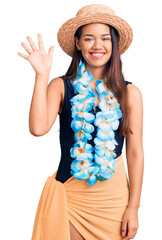 Young beautiful latin girl wearing hawaiian lei and summer hat showing and pointing up with fingers number five while smiling confident and happy.