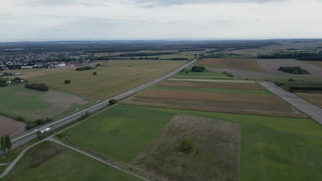 Panoramic aerial drone view of the highway that passes through the middle of the fields of the Alsace plain, with Bollwiller and the countryside around