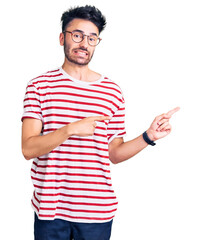 Young hispanic man wearing casual clothes pointing aside worried and nervous with both hands, concerned and surprised expression