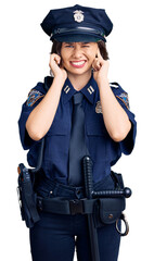 Young beautiful girl wearing police uniform covering ears with fingers with annoyed expression for the noise of loud music. deaf concept.