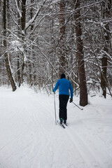 a man is skiing in the forest. Snow-covered white park