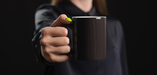 mockup of a black mug in female hands on a dark background