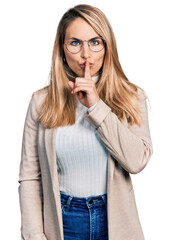 Young blonde woman wearing business shirt and glasses asking to be quiet with finger on lips. silence and secret concept.