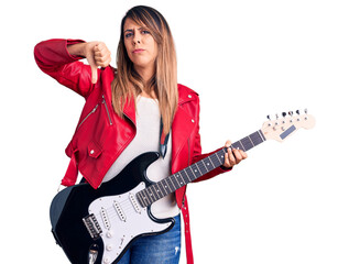 Fototapeta premium Young beautiful woman playing electric guitar with angry face, negative sign showing dislike with thumbs down, rejection concept