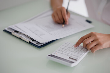 Asian woman using a calculator work at desk