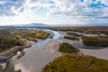 Aerial view of the river. Top view of the plain, river and forest. Mountains in the distance. Autumn season. September. Beautiful nature of Siberia. Ola River, Magadan Region, Russian Far East.