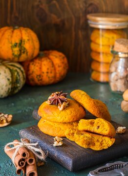  Pumpkin cookies with walnuts and spices on a wooden board on a green concrete background. Pumpkin recipes.