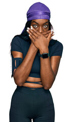 Young african american woman wearing sportswear shocked covering mouth with hands for mistake. secret concept.