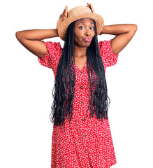 Young african american woman wearing summer hat doing bunny ears gesture with hands palms looking cynical and skeptical. easter rabbit concept.