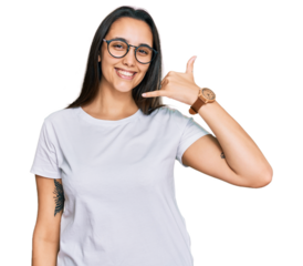 Young hispanic woman wearing casual white t shirt smiling doing phone gesture with hand and fingers like talking on the telephone. communicating concepts.