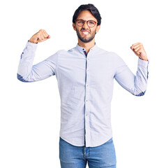 Handsome hispanic man wearing business shirt and glasses showing arms muscles smiling proud. fitness concept.