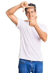 Young handsome man wearing casual white tshirt smiling making frame with hands and fingers with happy face. creativity and photography concept.