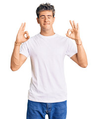 Naklejka premium Young handsome man wearing casual white tshirt relaxed and smiling with eyes closed doing meditation gesture with fingers. yoga concept.